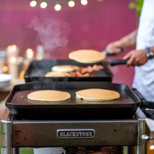 A-Blackstone-griddle-dont-show-the-brand-set-up-in-a-backyard-with-a-chef-flipping-pancakes-and-sizzling-bacon-in-the-background