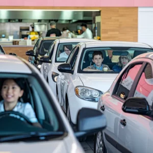 A-busy-weekend-scene-at-a-fast-food-drive-thru-with-families-in-cars-picking-up-lunch-orders