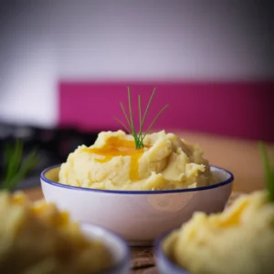 A-close-up-of-fluffy-mashed-potatoes-in-a-bowl-with-melted-butter-pooling-on-top-garnished-with-fresh-chives