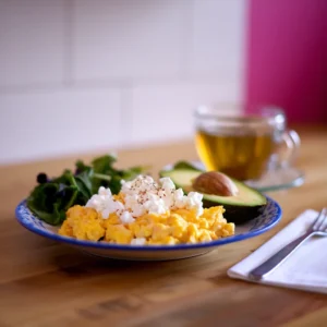 A-fitness-oriented-breakfast-plate-scrambled-eggs-with-cottage-cheese-avocado-slices-and-a-side-of-leafy-greens-paired-with-a-cup-of-green-tea