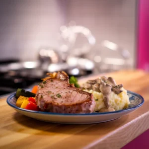 A-plate-featuring-bone-in-pork-chops-with-mashed-potatoes-topped-with-a-creamy-mushroom-sauce-served-with-a-side-of-roasted-vegetables