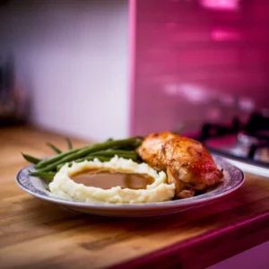 A-plate-featuring-mashed-potatoes-with-a-pool-of-gravy-paired-with-roasted-chicken-and-steamed-green-beans