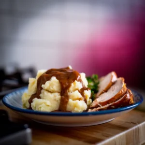 A-plate-of-mashed-potatoes-with-rich-brown-gravy-cascading-over-the-top-paired-with-roasted-chicken-or-turkey-slices