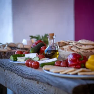 A-spread-of-Mediterranean-ingredients—olive-oil-fresh-vegetables-cheese-and-pita-bread—arranged-on-a-rustic-wooden-table